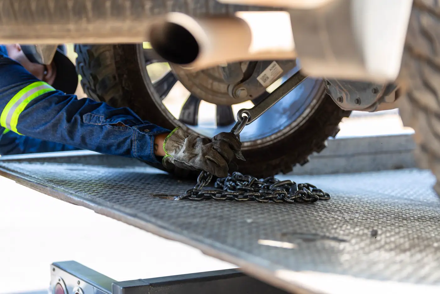 Operator chaining a truck wheel down to a flatbed deck