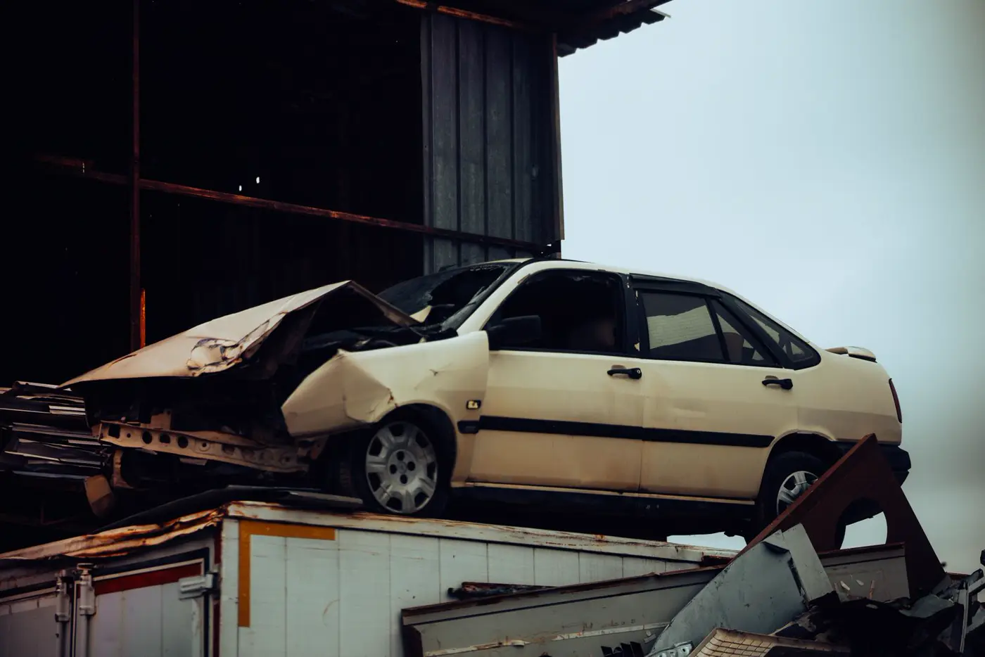 Crashed sedan sitting on top of a scrap metal heap