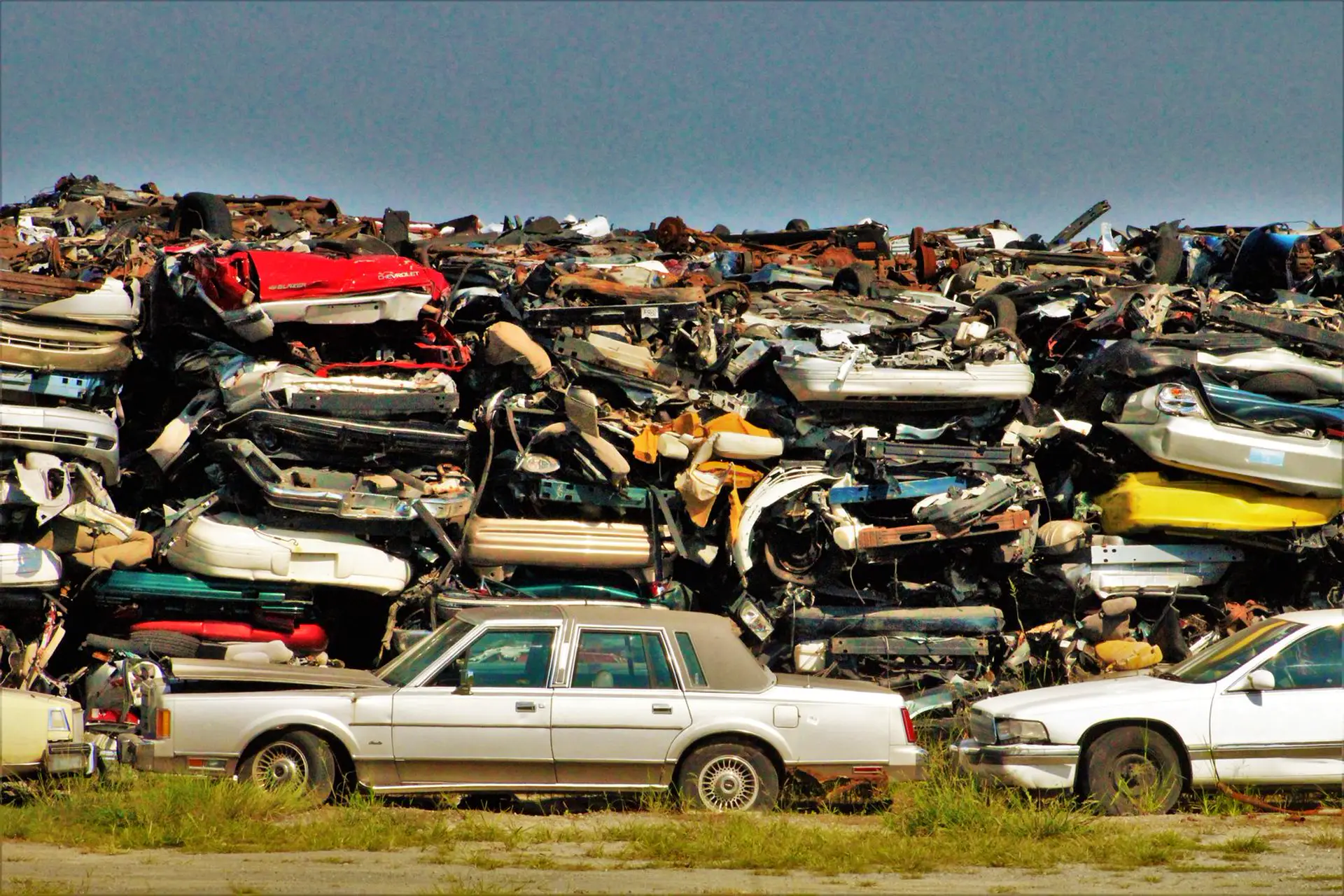 Wall of stacked junk cars waiting to be scrapped at a salvage yard