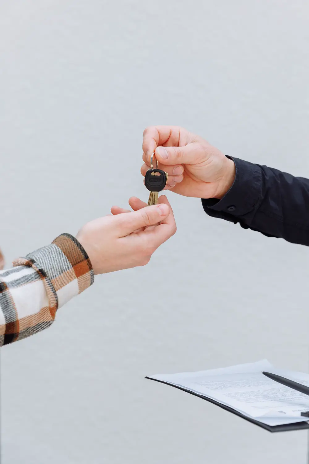 Hands exchanging car keys over paperwork