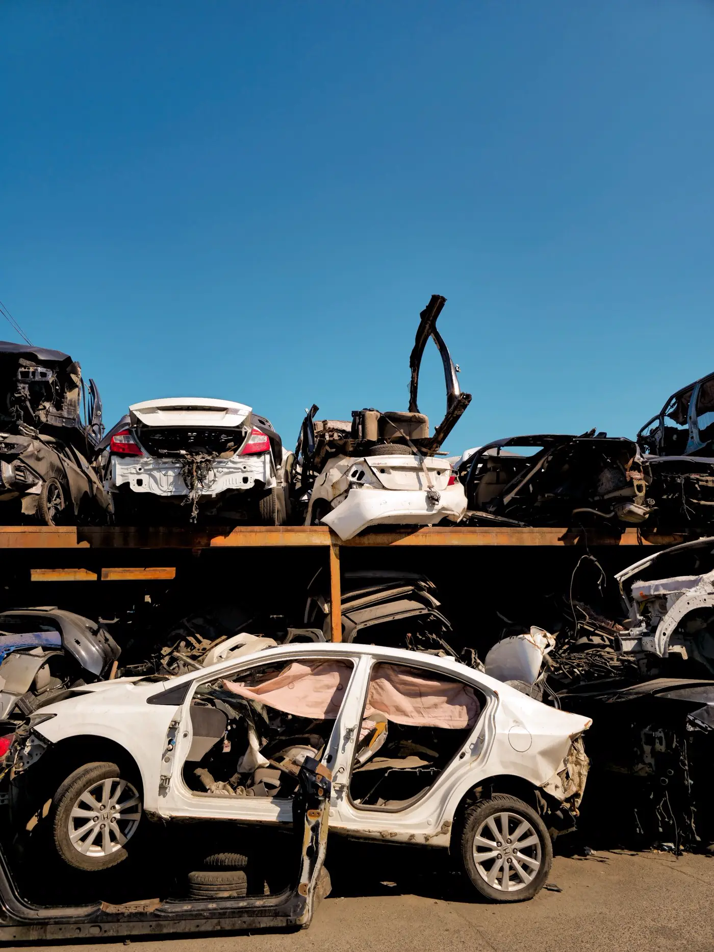 Salvage cars stored on steel racks under a blue sky